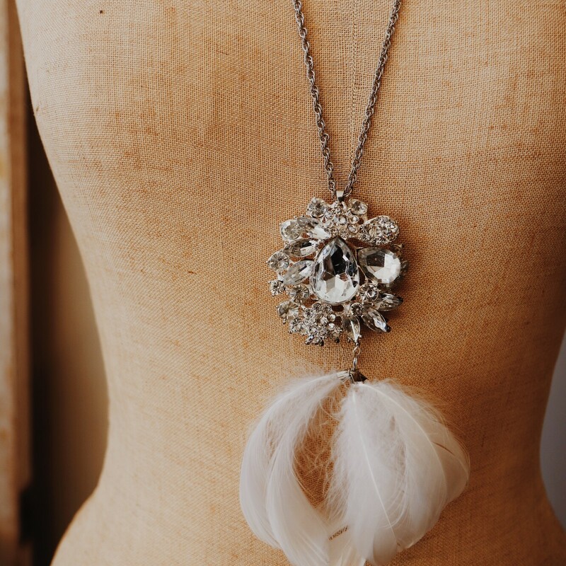 This elegant necklace is on a 30 inch chain and has a beautiful rhinestone pendant with feathers hanging from it!