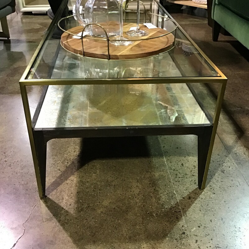 This coffee table is super on-trend! It features a brass (gold) frame and silver/gold detailing on the shelf under the glass. There is even some dark brown detailing to bring warmth to the piece! Love this table in front of our emerald green sofa!<br />
Dimensions are 51-1/2 in x 21-1/2 in x 16 in