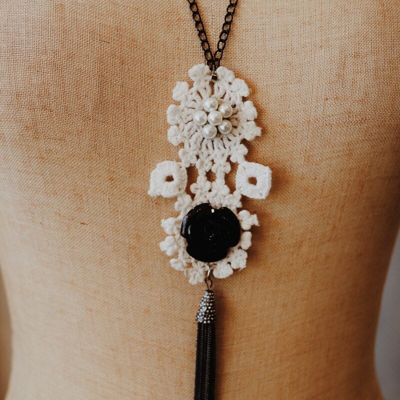 This Kelli Hawk Designs crochet necklace is on a black 27 inch chain. The pendant is a crochet piece with a black rose and a black chain tassel hanging from it.