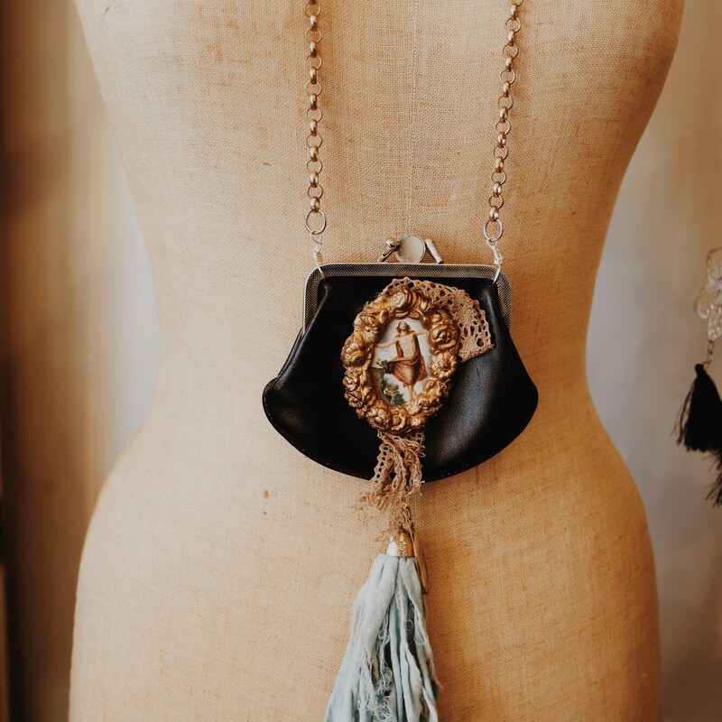 This Kelli Hawk Designs necklace is made from a vintage change purse and is on a 39 inch chain with a 3 inch extender. There is a religious picture on the front and a blue tassel.