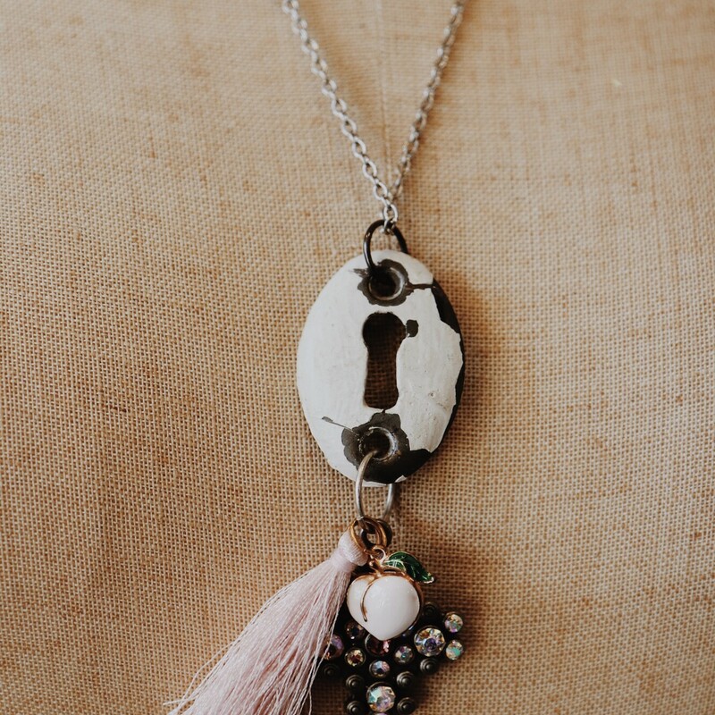 This beautiful Kelli Hawk Necklace has a vintage keyhole pendant with a rhinestone charm, a peach charm, and a tassel hanging from it! It is on a 24 inch chain.