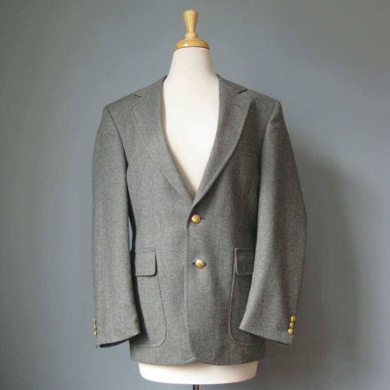 This is a simple mens gray blazer with gold buttons.<br />
The gray is light in color.<br />
Nicely tailored, single breasted, single vent in the back, high peaked lapels and large flap piockets.<br />
The front has three buttons, I show it with only the two top buttons buttoned as men in the sartorial know usually wear the bottom button open.<br />
Made in Hungary<br />
<br />
This jacket is so neutral it will work for guys or girls.  I love the idea of belting an oversized blazer with the perfect width (for your frame) leather belt.<br />
<br />
Fully lined, it has two chest pockets inside and a little ticket pocket<br />
100% wool.<br />
<br />
Flat Measurements:<br />
Armpit to Armpit: 22<br />
Length (back of neck to hem): 28 1/2<br />
Length of underarm sleeve seam: 15 1/2  (this is a bit shorter than average)<br />
<br />
Perfect condition.<br />
<br />
Thank you for looking.<br />
#43092