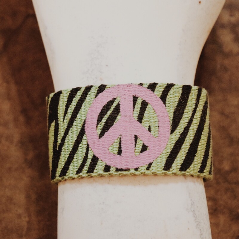 Green Zebra Striped Pink Peace Sign Cuff Bracelet. It is 2 inches wide, 8 inches long, and snaps in the back.