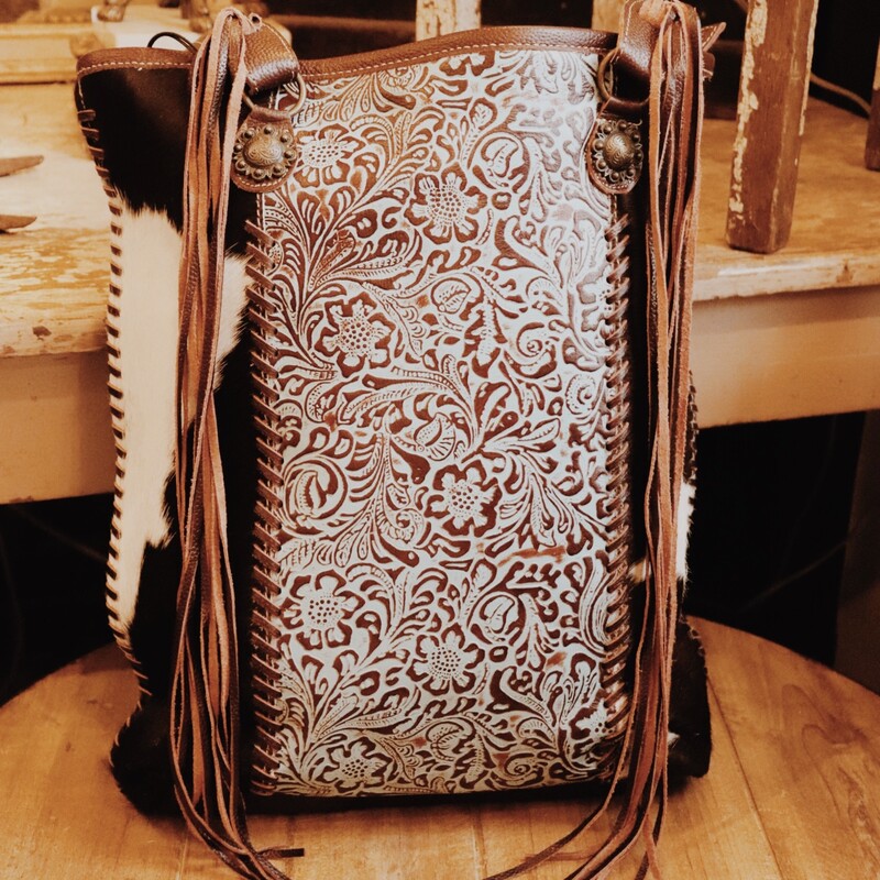 This Myra brand bag measures 15 inches long by 15 inches wide and is adorned by turquoise tooled leather, cowhide, and fringe! This bag has plenty of pockets for storage.