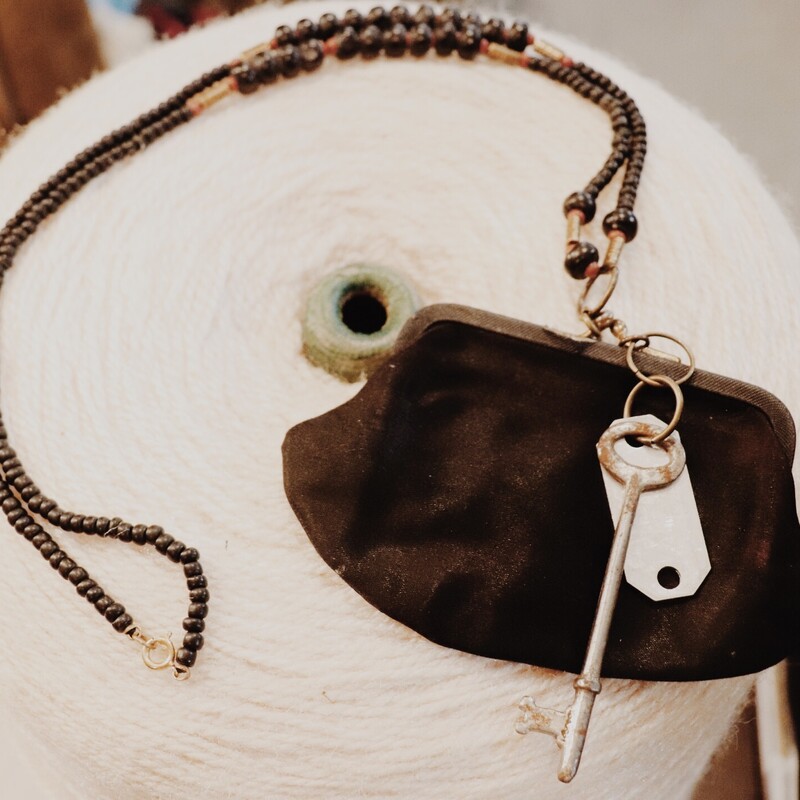 This black toned, handmade necklace is on a 29 inch beaded strand. The pendant is a black vintage coin purse!