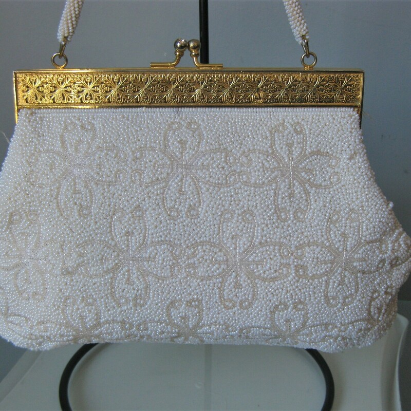 White beaded Frame bag from the 1960s.<br />
high quality gold metal frame with modeled relief and jeweled tilt clasp.<br />
the frame opens wide which is really usefull.  Roomy interior lined with white satin with a few slip pockets.<br />
Single beaded handle.<br />
Made in British Hong Kong by Grande Maison Blanche<br />
<br />
Great condition, with some brownness on a few beads on one side and some rust stains on the inside.<br />
<br />
Width 7<br />
Height: 6.75<br />
Depth: 1.5<br />
Handle Drop: 5.75<br />
thank you for looking!<br />
#43958