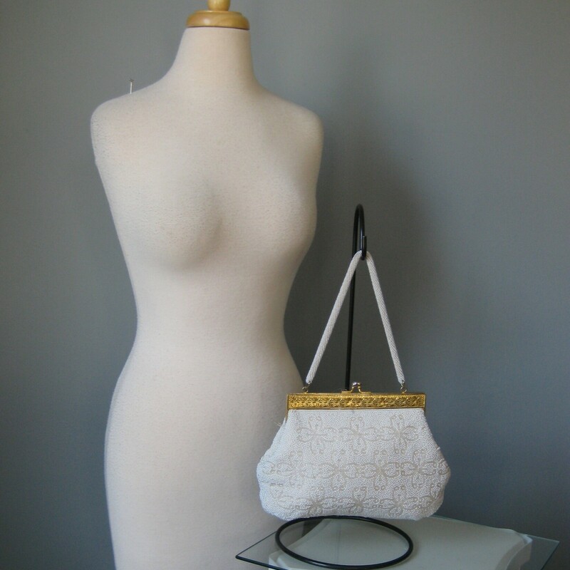 White beaded Frame bag from the 1960s.
high quality gold metal frame with modeled relief and jeweled tilt clasp.
the frame opens wide which is really usefull.  Roomy interior lined with white satin with a few slip pockets.
Single beaded handle.
Made in British Hong Kong by Grande Maison Blanche

Great condition, with some brownness on a few beads on one side and some rust stains on the inside.

Width 7
Height: 6.75
Depth: 1.5
Handle Drop: 5.75
thank you for looking!
#43958