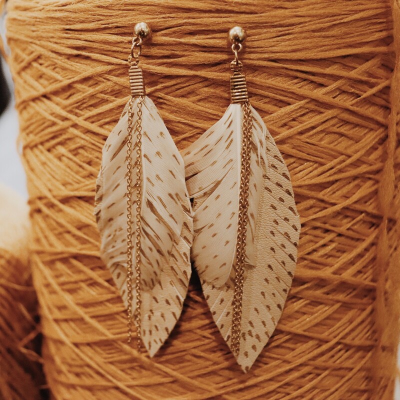 Feather Earrings, with one real feather and one leather made feather and gold speckle detail, along with cmall gold chains hanging from the earring loop. Measuring 4.5 inches long and light as a feather.