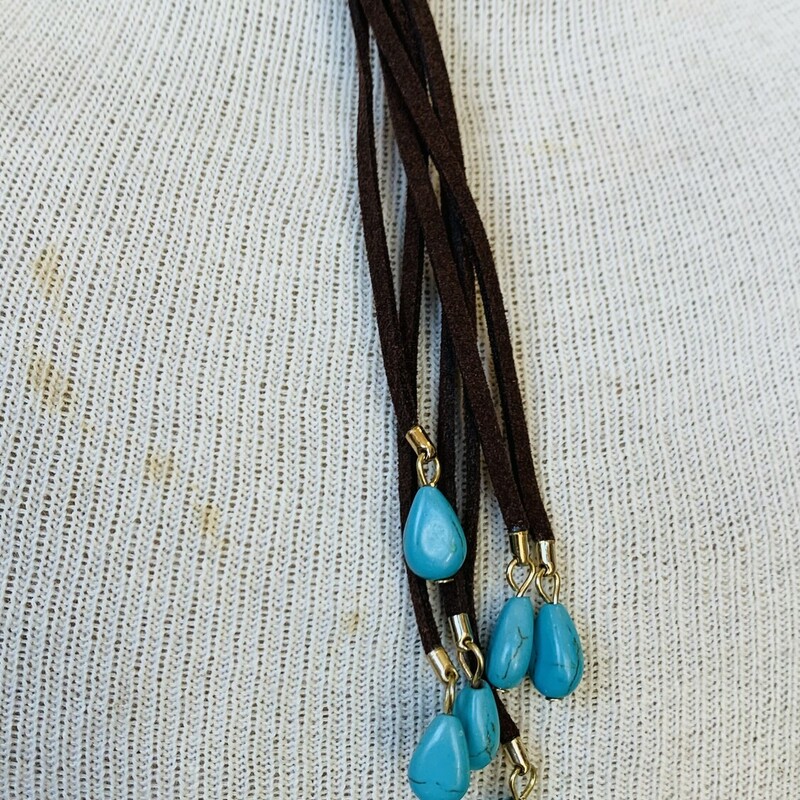 Brown Leather Choker with tassles hanging from the center and silver and turqouise bead hanging on the tassle. Measuring 6 inches in diameter with 4 inch tassles and a 2 inch adjustable clasp.