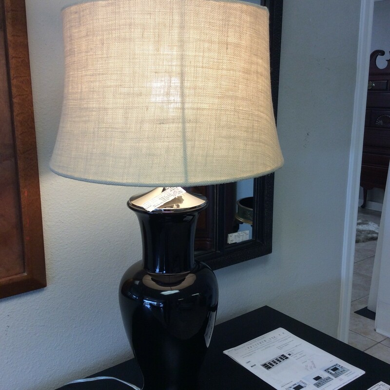 By Martha Stewart, this lamp features a jet black urn shaped base with chrome and a burlap shade.