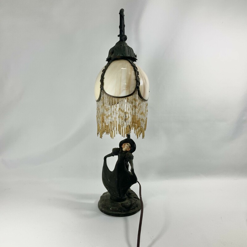 Art nouveau table lamp bronze  Depicts a lovely woman in a flowing dress and wide brimmed hat  Amber colored glass shade with beaded fringe
Floral  accents
Good condition needs some attention to get it to work again hat shows a scratch on the brim
21 inches high