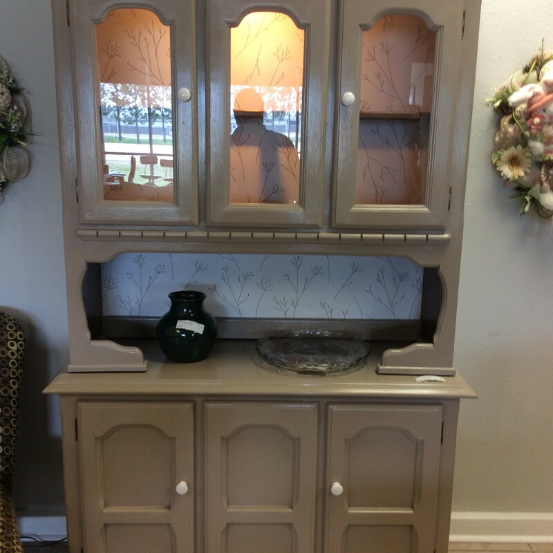 This is a charming little china cabinet with a painted grey finish. The upper cabinet is lit and has a whimsical wallpaper backing.