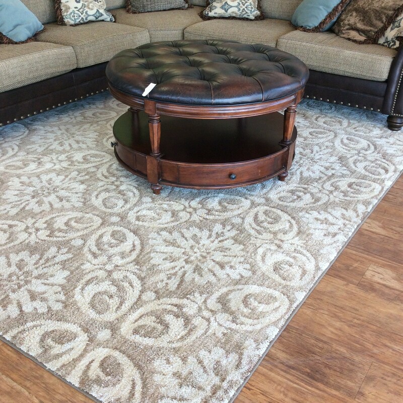 This area rug features a light brown, tan and cream floral pattern.