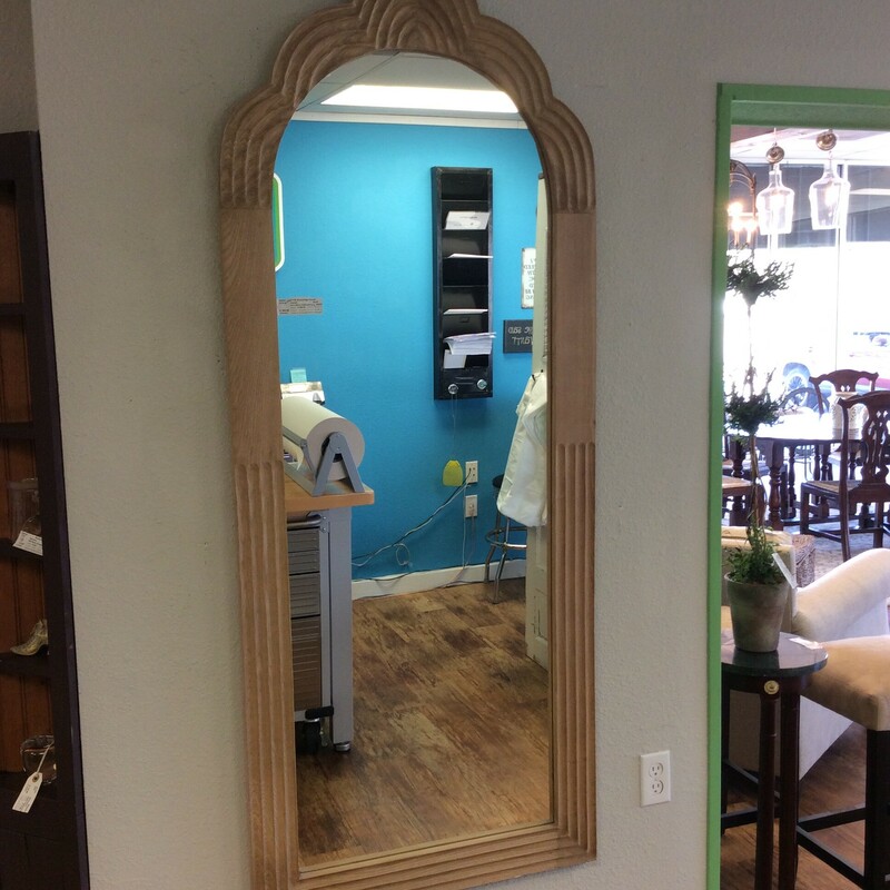 This mirror from Anthropology has a light wood frame with a scalloped top.