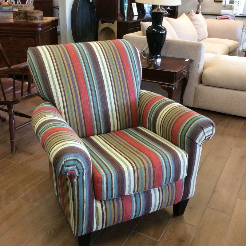 This armchair is upholstered in a striped pattern of many colors including purple, cherry, teal, brown, cream and more.