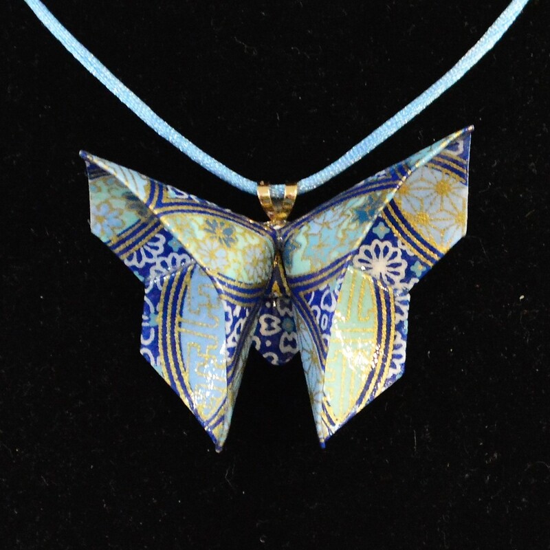 Rich Gray
Blue Origami Butterfly Necklace
Paper  2 x 2.5 inches
Origami butterfly folded from paper with shades of blue and gold highlights.  Coated with clear acrylic sealants for durability and hung on an 18 inch blue cord.