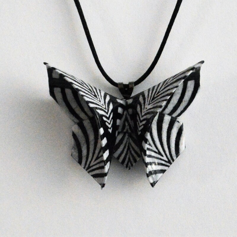 Rich Gray
Black and White Origami Butterfly Necklace
2 x 2.5 inches on 18 inch cord
Folded from a black and white zebra leaf patterned lokta paper from Nepal.  Coated with acrylic sealants for durability.