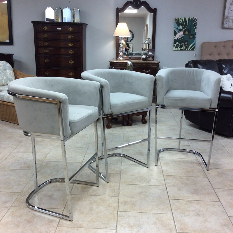 This set of 3 barstools are contemporary in style. They feature a shiny, chrome frame and are upholstered in a soft gray.