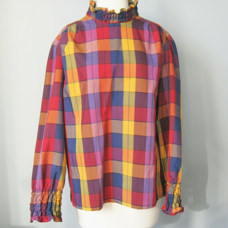 This plaid shirt from the 1970s was made by Essentially Separate
The fit is relaxed and the medium scale plaid is a soothing mix of muted colors in navy and burgundy with a pop of yellow.
the fabric is quite lightweight
It has a high neck and both the neck and the ends of the long sleeves are elasticized for a ruffled effect.
Elastic loop and button at the back of the neck.
80% poly, 20% cotton

Should fit a modern size large (marked size 18, but probably a bit small for a modern size 18)

Here are the flat measurements of this shirt, please double where appropriate:
Armpit to Armpit: 2: 2 1/2
Width at hem: 24
Length: 24
shoulder to shoulder: 17 (no sh pads)
nderarm sleeve seam: 17.25
Length: 22 1/2
Perfect condition.

Thanks for looking.
#40995