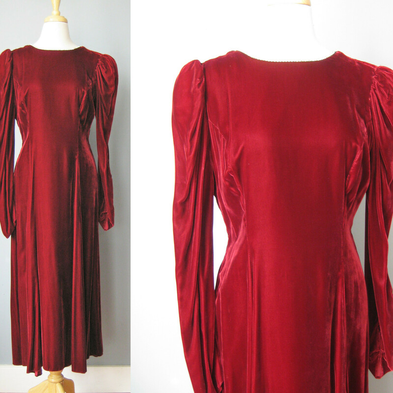 A deep rich red rayon / burgundy velvet gown from the 1980s.
Very dramatic with puffed sleeves, a high neck and a deep v open back.
The entire neckline, from and back opening are decorated with a single row of metal set rhinesontes.
 small, a bit subtle but will definitely sparkle.
The long sleeves end in a point giving the look a very renaissance feel. snap closure here
Bodice is lined
Skirt is full and fluid
Colored union label
made in the USA
It's just gorgeous and in amazing condition!

It's marked size 18 but please use measurements below, will be better on a modern size medium
Shoulder to shoulder: 14.5
armpit to armpit: 18.25
waist: 16.5
hip: up to 23
Underarm sleeve seam length: 16.5
length: 49 (probably ankle length depending on how tall you are)

Thanks for looking!
#38056
