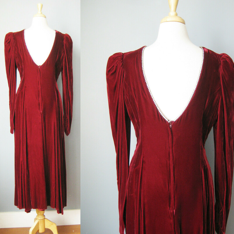 A deep rich red rayon / burgundy velvet gown from the 1980s.<br />
Very dramatic with puffed sleeves, a high neck and a deep v open back.<br />
The entire neckline, from and back opening are decorated with a single row of metal set rhinesontes.<br />
 small, a bit subtle but will definitely sparkle.<br />
The long sleeves end in a point giving the look a very renaissance feel. snap closure here<br />
Bodice is lined<br />
Skirt is full and fluid<br />
Colored union label<br />
made in the USA<br />
It's just gorgeous and in amazing condition!<br />
<br />
It's marked size 18 but please use measurements below, will be better on a modern size medium<br />
Shoulder to shoulder: 14.5<br />
armpit to armpit: 18.25<br />
waist: 16.5<br />
hip: up to 23<br />
Underarm sleeve seam length: 16.5<br />
length: 49 (probably ankle length depending on how tall you are)<br />
<br />
Thanks for looking!<br />
#38056