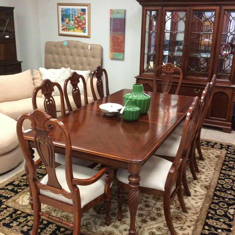 This diningroom set is by Lexington Furniture. It includes 8 upholstered chairs and 2 leaves. It features a dark wood finish and carved details.