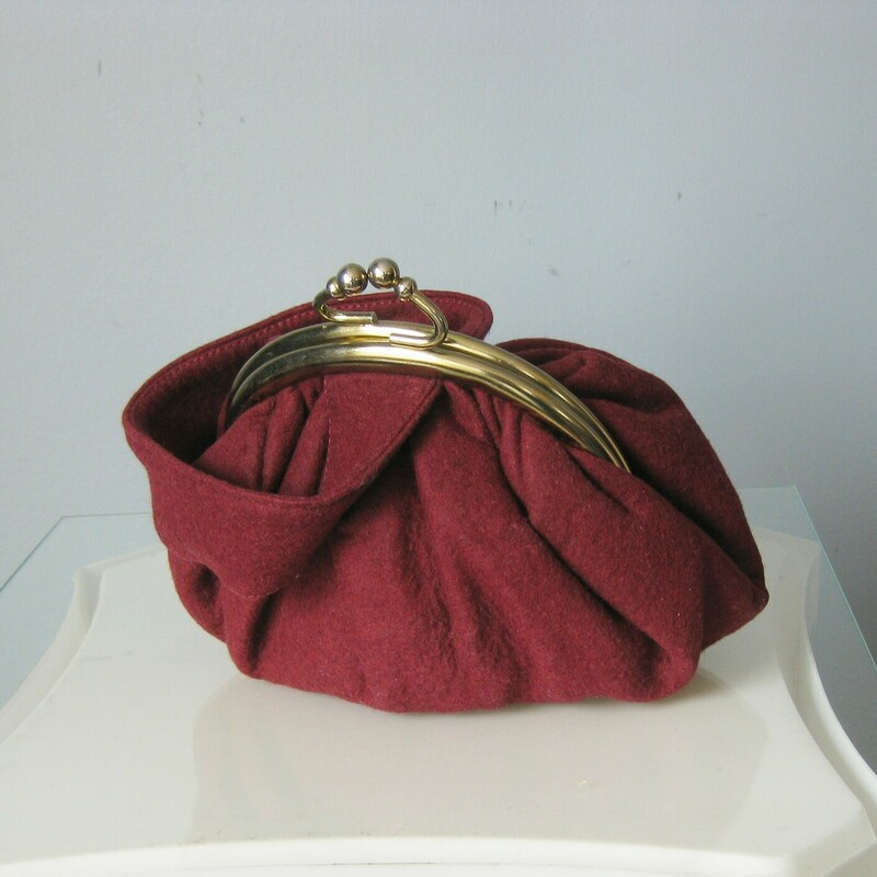 Roudish burgundy vintage wrislet or reticule in wool felt.  Very feminine.  Gold half circle frame with pretty kiss lock clasp.<br />
No Tags<br />
Fabric lining<br />
<br />
Excellent condition.<br />
<br />
Width: 9<br />
Height: 5.5<br />
Depth: 35<br />
Handle drop: 8 1/2<br />
<br />
Thanks for looking!<br />
#42117