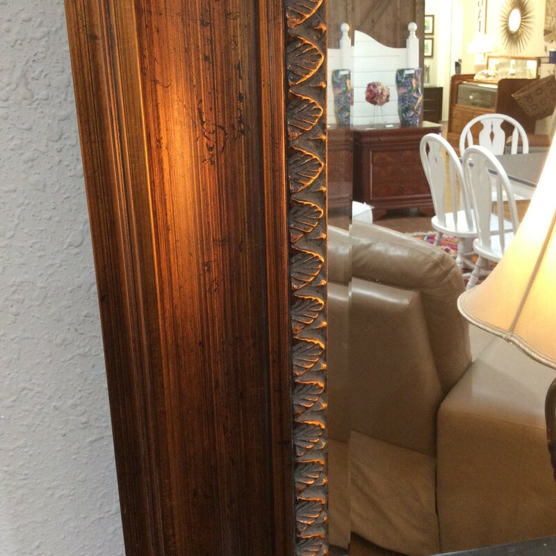 This lovely mirror features beveled glass and a bronzed wood frame.