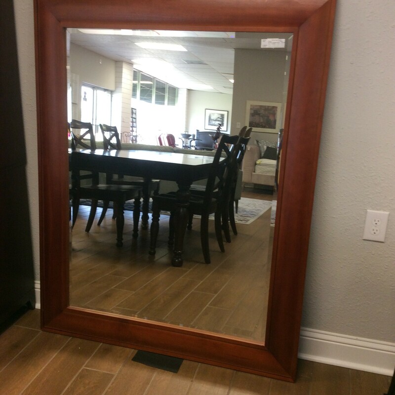 This is a large mirror with beveled glass and a simple redwood frame.