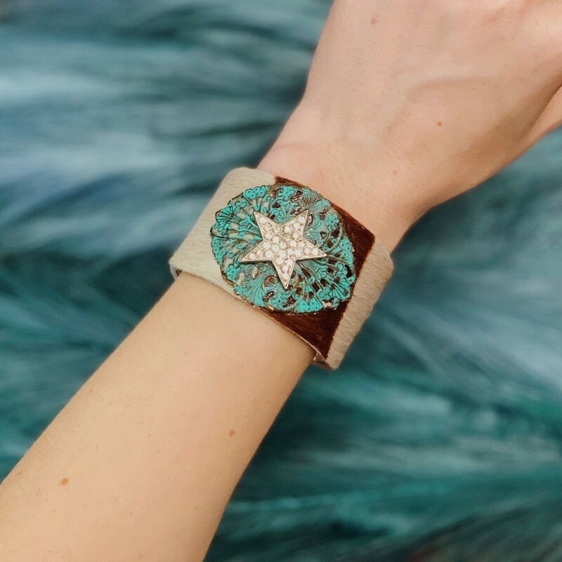 This cowhide, turquoise, star cuff is absolutely adorable! Handmade by Kelli Hawk Designs, this cuff has a layer of leather cowhide over the front with a turquoise metal piece and a rhinestone star on top!