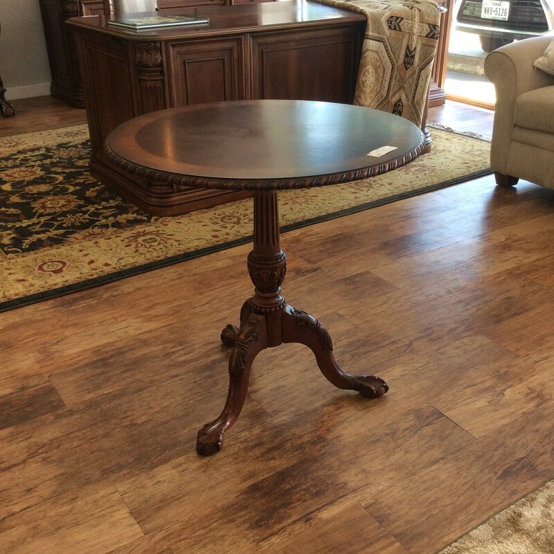 This round pedestal side table features a dark wood finish, detailed carvings and 3 claw foot legs.