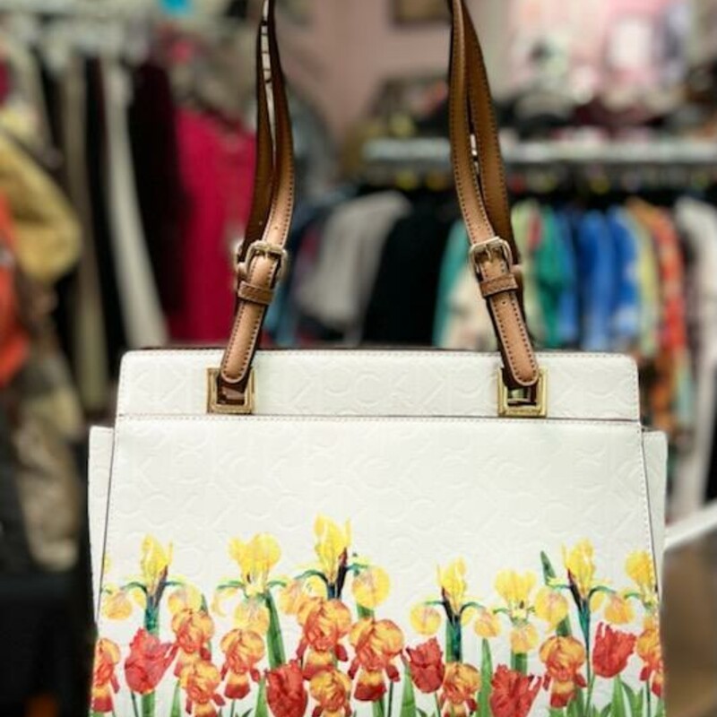 Floral Calvin Klein Tote<br />
??White with daffodils<br />
??Very spacious<br />
??Signature design purse Flowers Yellow white red green brown.<br />
- metal gold<br />
-satchel with Dual carry handles and  Magnetic closure -Logo detailing with allover monogram logo motif -multiple interior pockets, Interior center zip divider pocket + 2 open compartments Interior zip pocket + 2 slip pockets<br />
IN LIKE NEW CONDITION<br />
Original Retail Price: $158.00