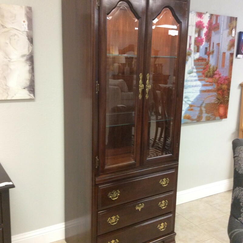 This is a Kincaid Curio Cabinet with a Dark Cherry Wood Finish. This Curio has 3 drawers, beautiful gold hardwear, 2 adjustable glass shelfs and 2 overhead lights.