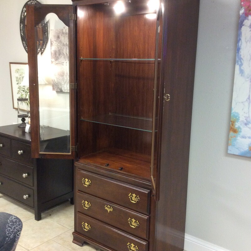 This is a Kincaid Curio Cabinet with a Dark Cherry Wood Finish. This Curio has 3 drawers, beautiful gold hardwear, 2 adjustable glass shelfs and 2 overhead lights.