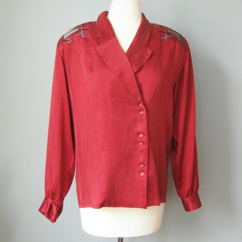 Gary Fabrikant washed silk blouse in deep almost burgundy red.
Bit shoulder pads support a decorative shoulder and back yoke, embroidered and appliqued with gray, teal and red geometric designs.
Asymmetrically set buttons pair off down the front
Button Cuff Sleeves.
Nicely made with an interior button to keep that neckline under control.
Perfect condition.
flat measurements:
shoulder to shoulder: 20
armpit to armpit: 20
length: 25.5
Underarm sleeve seam length: 18
Width at hem:  19.5

thanks for looking!
#45422