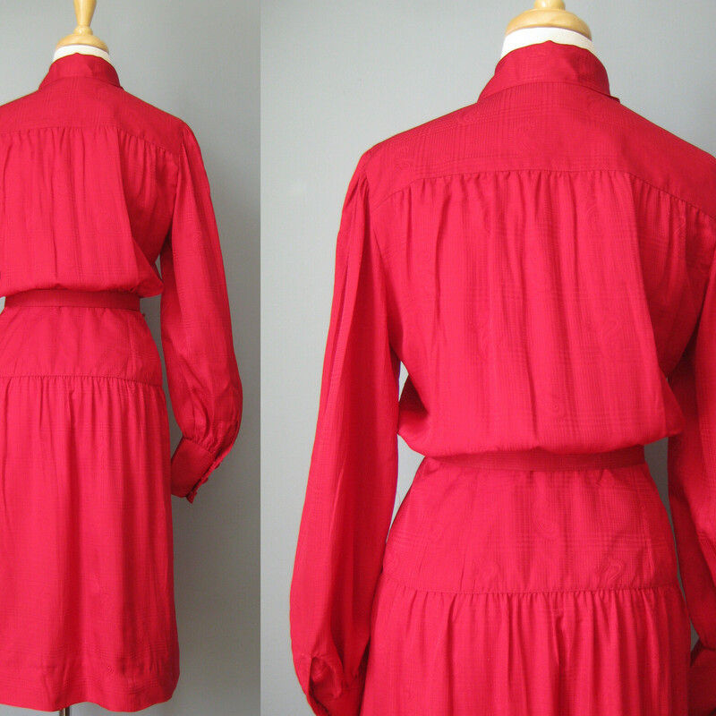 Here is a pretty red silk paisley jacquard secretary dress from the 1980s.<br />
by Adele Simpson, made in Hong Kong with high end dressmaker details<br />
High neck with sash bow tie.<br />
Dropped waist<br />
Matching belt<br />
interior waist stay<br />
Full skirt and puffy sleeves<br />
Unlined<br />
Long sleeves<br />
<br />
Flat measurements:<br />
Shoulder to shoulder: 14.75<br />
armpit to armpit: 20<br />
Waist: 13<br />
Hip: up to 20<br />
Length: 42<br />
Underarm sleeve seam: 18 (sleeve buttons at the end)<br />
<br />
perfect condition!<br />
<br />
Thanks for looking!<br />
#42921