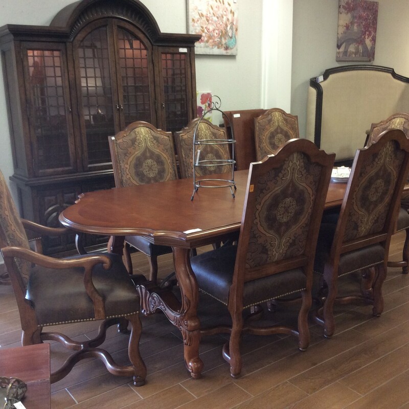 This high stlye dining room set by Century has beautiful  carving with a cherry finish. The chairs have leather seats and upholstered backs.