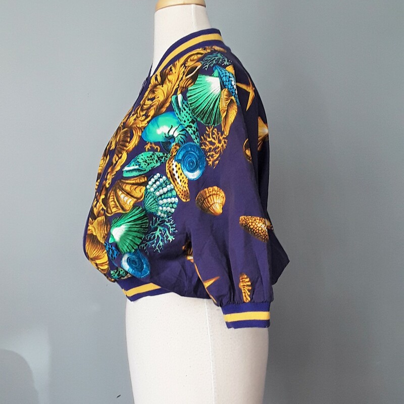 Ali Miles Baroque Sea The, Purple, Size: Large<br />
Lightweight Cotton Blend Jacket with a fantastic baroque sea themed print.<br />
Purple with gold seashells, starfish and acanthus leaves.<br />
Short sleeves, with sweater cuffs, also sweatery edge at the bottom<br />
Front Zipper<br />
Unlined<br />
50% cotton, 50% poly<br />
By Ali Miles<br />
Made in the USA<br />
Perfect condition!<br />
Marked size 12.<br />
flat measurements:<br />
shoulder to shoulder: 21.75<br />
armpit to armpit: 25<br />
length: 20.5<br />
<br />
thanks for looking!<br />
#45604