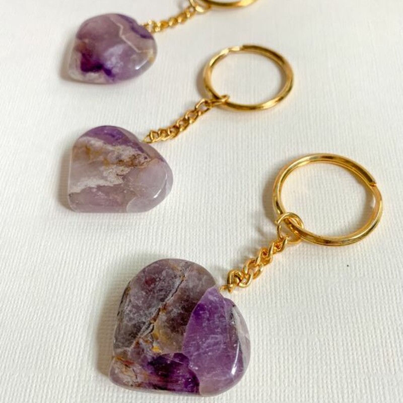 Amethyst Crystal Keychain, Purple<br />
Carry the power of crystal energy with you, with these adorable natural gemstone keychain.<br />
<br />
Heart- shaped hand carved crystals are attached to sturdy gold color chain and ring.<br />
<br />
Amethyst Healing Properties<br />
• Promotes intuition, calm and stillness<br />
• Eliminates stress and worry<br />
• Works with crown chakra<br />
<br />
Key chain measures 3.25 inches long<br />
Heart measures 1.2 inch across<br />
<br />
Note: Crystals may vary slightly by color and size