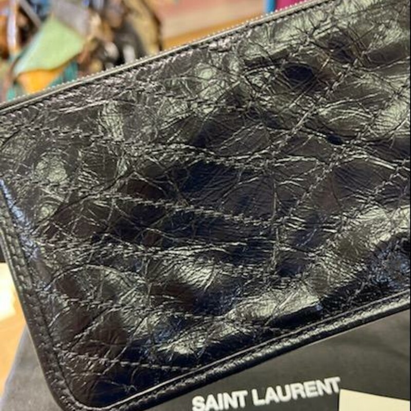 Saint Laurent Niki Bill Pouch In Crinkled Vintage Leather<br />
After creating 20 (and counting) different versions of the wildly popular Monogram Bill Pouch, Saint Laurent has finally introduced an all-new silhouette to the range, one that’s simply known as the Niki Bill Pouch which comes in crinkled vintage calfskin leather. Think of it as the softer, curvier sister that’s a great alternative for those who prefer a casual-looking piece (as opposed to the sharp and structured Monogram Bill Pouch), while retaining standard features such as the flat front pocket and central zipped compartment. Besides, it comes in the handy 21 cm by 13 cm size, which will fit a good deal of cards along with a stack of fifty dollar bills which you will never have to fold or worry about getting creased.<br />
What’s new about the Niki Bill Pouch? The YSL initials in front are entirely tone-on-tone, which is great news if you’re constantly worried about metal getting scratched or tarnished. Not only are the curved corners (at the base) pleasing to the eye, it also makes it slightly more resistant to wear and tear, scoring extra points in terms of longevity and usage.<br />
Description:<br />
-From the 2019 Collection by Anthony Vaccarello<br />
-Black Leather<br />
-Tonal Hardware<br />
-Single Exterior Pocket<br />
-Canvas Lining & Single Interior Pocket<br />
-Zip Closure at Top<br />
Details:<br />
-Height: 5.25\"<br />
-Width: 8.25\"<br />
-Depth: 0.25\"<br />
FASHIONPILE resale, has this bag available now for $450.00.<br />
TheReal Real has it for resale for $435.00 (in our condition) & $346.50 (signs of wear)<br />
BONUS:  This bag does come with the Original Dust, cards and the Original Box.  This can easily be gifted.<br />
Like New Condition!