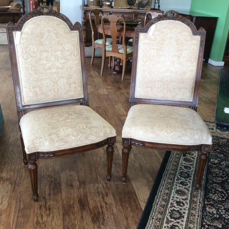 This pair of French Country chairs are upholstered in an ivory brocade fabric and have carved details on the frames.