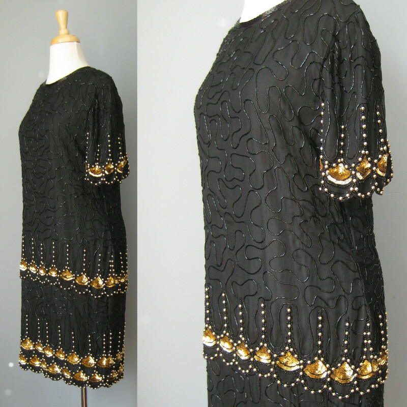 Vtg L. Kazar Beaded, Black, Size: XL<br />
This spectacular sequined silk cocktail dress from the 1980s is perfect for festive evening occasions.    Especially if the event has a Roaring Twenties Theme.<br />
The straight silhouette, emphasized by vertical design lines is both flattering and evocative of the era.<br />
The dropped waist with inverted and stylized papyrus symbols evokes Ancient Egypt a favorite design inspiration in the 1920s.<br />
<br />
The silk shell is fully lined. There is no stretch to this garment, it has a zipper in the center of the back.<br />
The dress is by Lawrence Kazar.<br />
<br />
Here are the flat measurements, please double where appropriate:<br />
Shoulder to Shoulder: 16<br />
Armpit to Armpit: 21<br />
Waist: 17<br />
Hips: 20<br />
Length from back of neck to hem: 38<br />
<br />
The dress itself is in excellent condition.  As is almost always the case with these dresses with overall beading, there are a few beads missing in the seat area.<br />
<br />
<br />
Thank you for looking!<br />
#42887