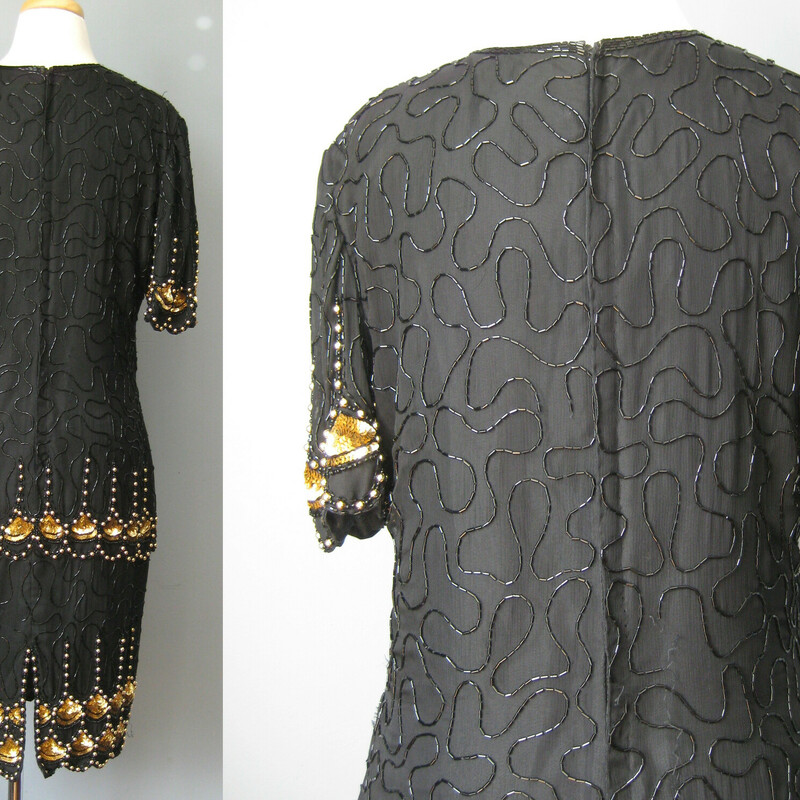 Vtg L. Kazar Beaded, Black, Size: XL<br />
This spectacular sequined silk cocktail dress from the 1980s is perfect for festive evening occasions.    Especially if the event has a Roaring Twenties Theme.<br />
The straight silhouette, emphasized by vertical design lines is both flattering and evocative of the era.<br />
The dropped waist with inverted and stylized papyrus symbols evokes Ancient Egypt a favorite design inspiration in the 1920s.<br />
<br />
The silk shell is fully lined. There is no stretch to this garment, it has a zipper in the center of the back.<br />
The dress is by Lawrence Kazar.<br />
<br />
Here are the flat measurements, please double where appropriate:<br />
Shoulder to Shoulder: 16<br />
Armpit to Armpit: 21<br />
Waist: 17<br />
Hips: 20<br />
Length from back of neck to hem: 38<br />
<br />
The dress itself is in excellent condition.  As is almost always the case with these dresses with overall beading, there are a few beads missing in the seat area.<br />
<br />
<br />
Thank you for looking!<br />
#42887