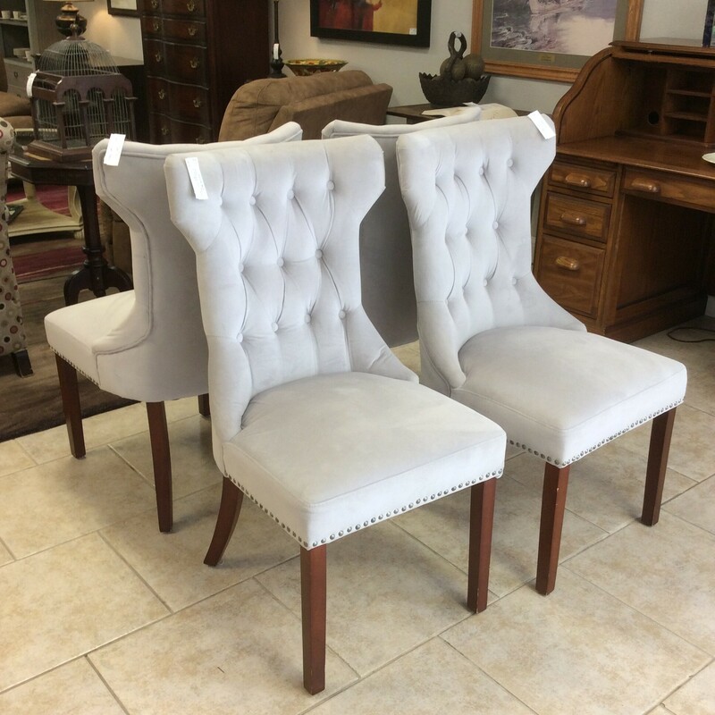 This a set of 4 grey, upholstered, tuffed chairs. These chairs have a nailhead trim and dark wood legs.