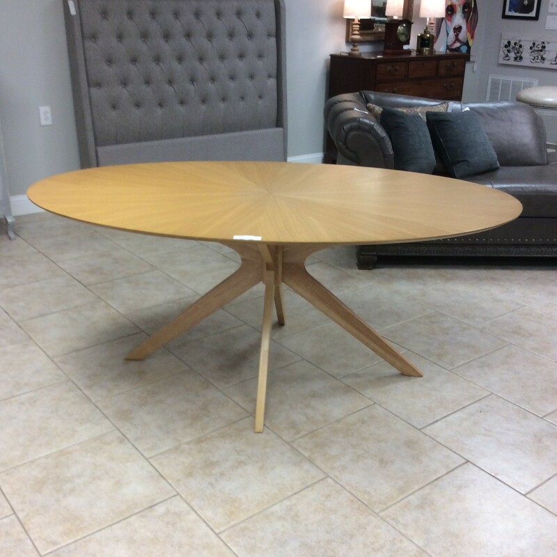 This oval Stesha table has a sleek mid-century design in a blonde wood finish.