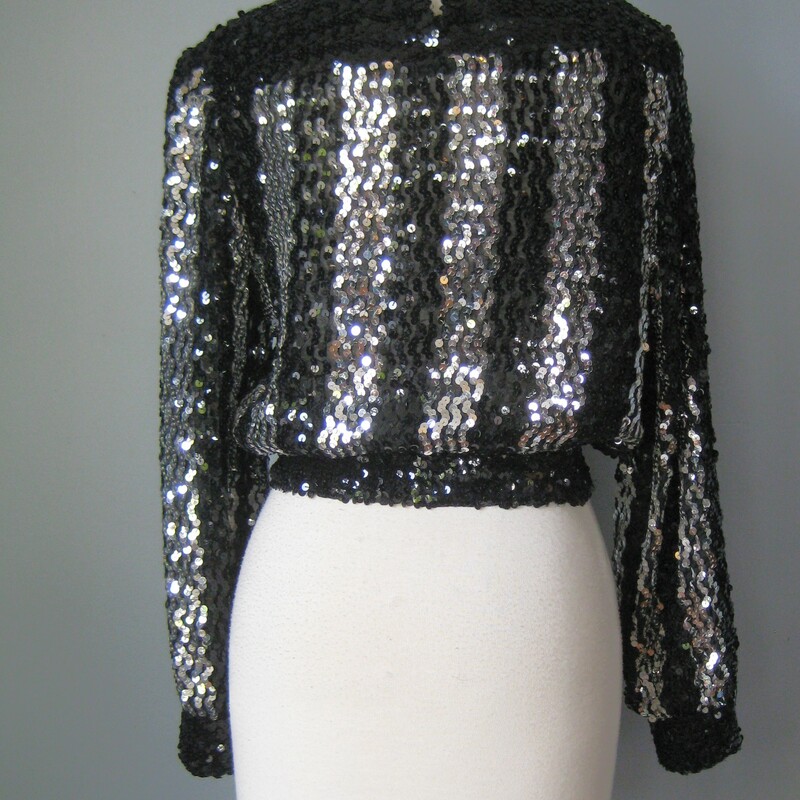 Vtg Caron Sequined Top, Black, Size: Medium<br />
Fun sweater for evening.<br />
Black and silver sequins arranged in wide vertical stripes on the front, back and sleeves.<br />
It has a kind of baseball jacket/sweatshirt silhouetter, elasticized at cuffs and waist and somewhat cropped.<br />
Squarish neckline<br />
unlined<br />
Quite stretchy overall, including the waistband but the cuffs have lost a good deal of their snap.<br />
by Caron, cute label<br />
Made in the USA<br />
<br />
Flat measurements:<br />
shoulder to shoulder: 16<br />
armpit to armpit: 20 unstretched<br />
waist: 13.75 stretches comfortably to 17<br />
length: 20<br />
<br />
Thanks for looking!<br />
#43429