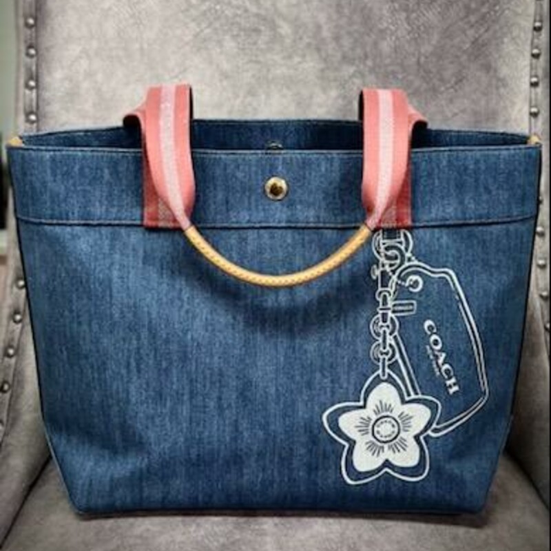 This AUTHENTIC Coach® Graphic Denim Tote is destined to become your favorite 3-season bag. Its versatility and usage possibilities are endless. It is crafted of canvas and leather. The exterior features a fun and fanciful graphic Coach® tag design. It is designed to, and replaces the \"usual\" leather \"tag\" that typically hangs from Coach® bags. The double straps are striped in solid rose and pale pink glitter. The bag closes with a button and opens to a large compartment (1) zippered pocket and (2) slide pockets. This bag is ideal for everyday use, to take to the pool or beach, or dress it up for evening out!
It measures 13\"W x 6\"D x 11.75\"T. The handle\"s\" drop is 10\".
This bag is in like new condition with no flaws.
Original retail price is $278.00