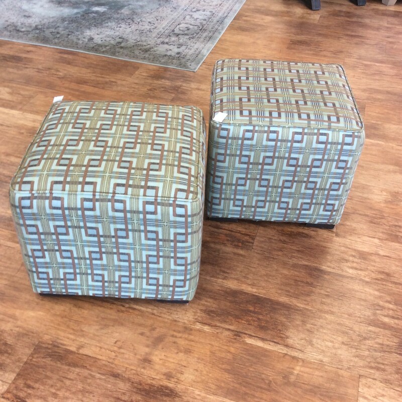 This pair of upholstered cube ottomans are covered in a green geometric fabric.