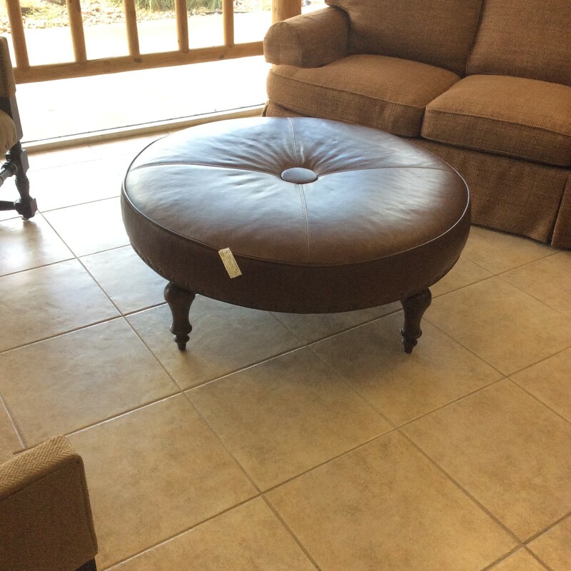 This is a Brown, Round, Tuffed,  Leather Ottman with nailhead trim.