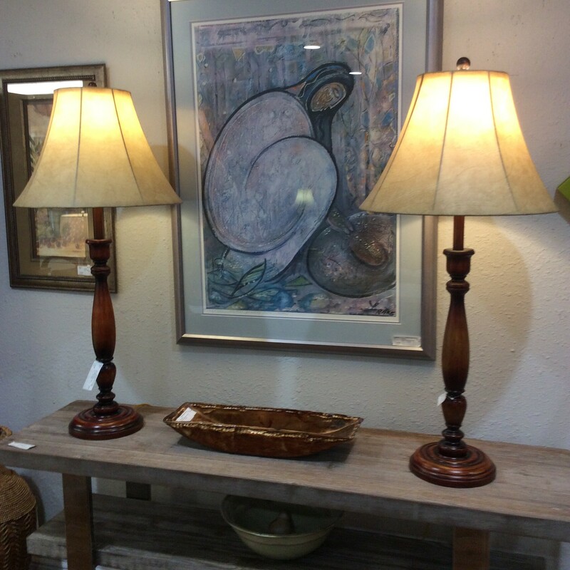 This is a pair of wood tone brown lamps with a cream   leather shade.
